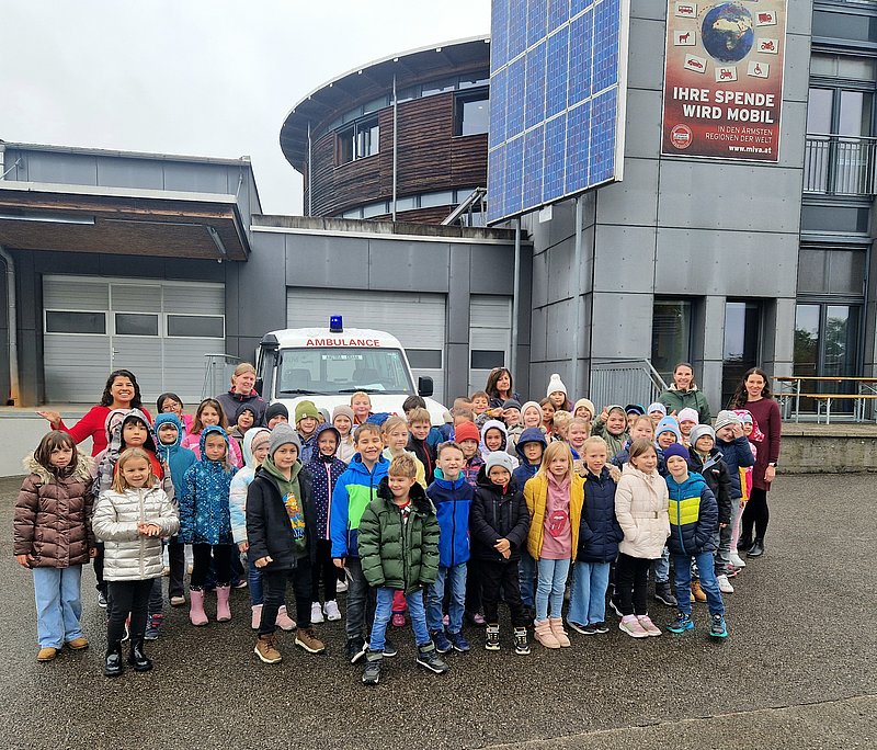 Eine Gruppe von Kindern und Erwachsenen posiert vor einem Krankenwagen 